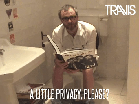 Man Sitting on Toilet Holding Book