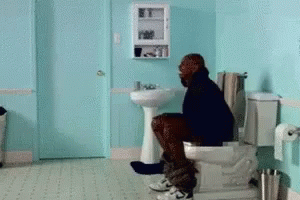 Man Sitting on Toilet in Blue Bathroom