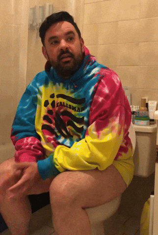 Man Sitting on Toilet Wearing Tie Dye Calimar Shirt
