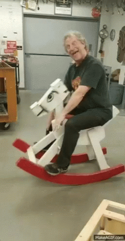 Man Sitting On Wooden Rocking Horse Smiling GIF