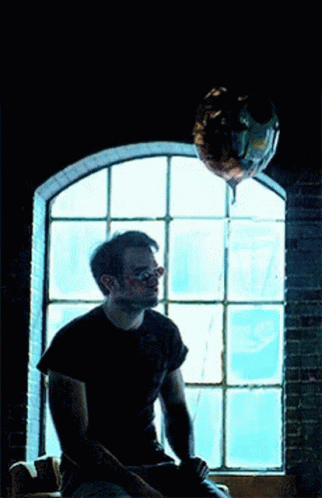 Man Sitting Under Balloon by Window