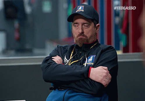 Man Sitting With Arms Crossed Wearing Ted Lasso Hat