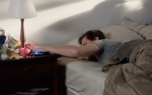Man Sleeping in Bed Next to Lamp and Nightstand