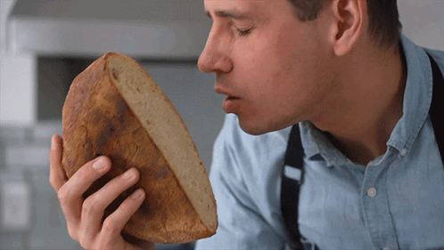 Man Smelling Loaf of Bread