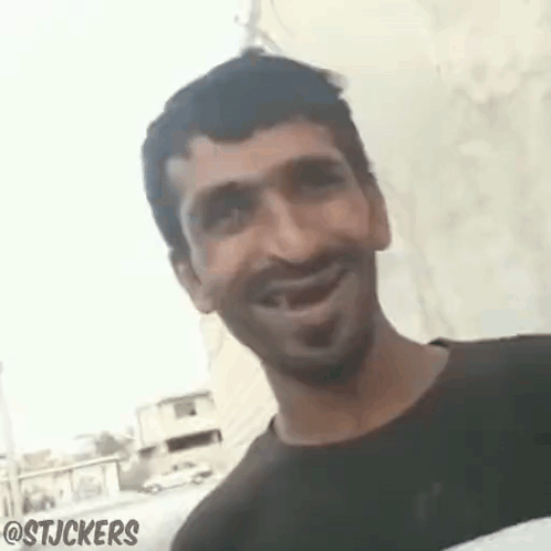 Man Smiling And Looking At Camera In Front Of Wall GIF