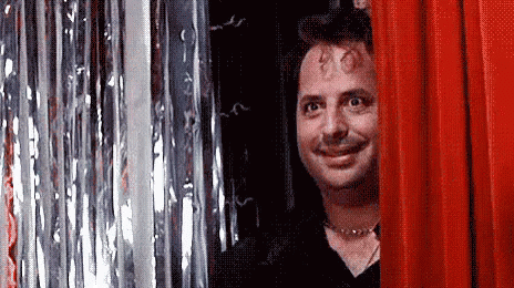 Man Smiling Behind Red Curtain