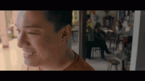 Man Smiling in Room With People at Tables