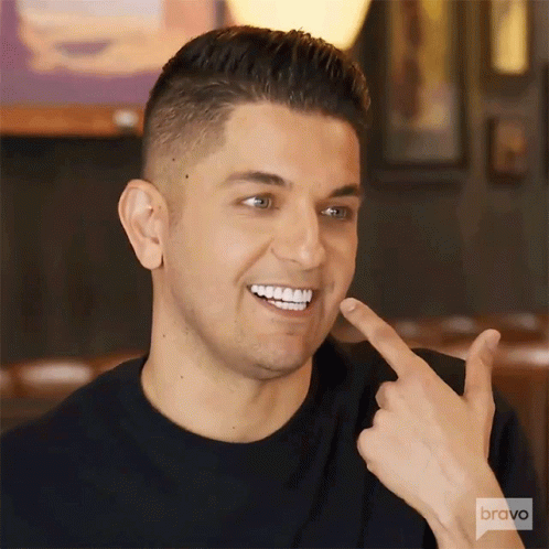 Man Smiling Pointing At Teeth In Bravo Shirt GIF