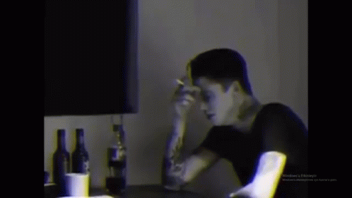 Man Smoking Cigarette at Table with Alcohol