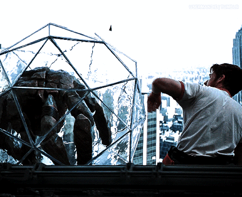 Man Smoking Cigarette Looking at Spider in Glass Cage