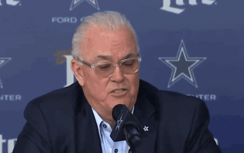 Man Speaking Into Microphone in Front of Ford Sign