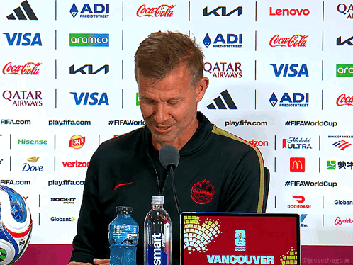 Man Speaking Into Microphone In Front Of Qatar Airways Ads GIF