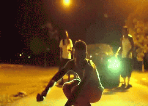 Man Squatting in Front of Car With Light