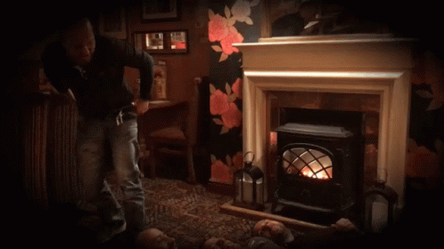 Man Squatting in Front of Fireplace With Lantern