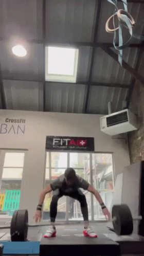 Man Squatting in Front of Fit Sign