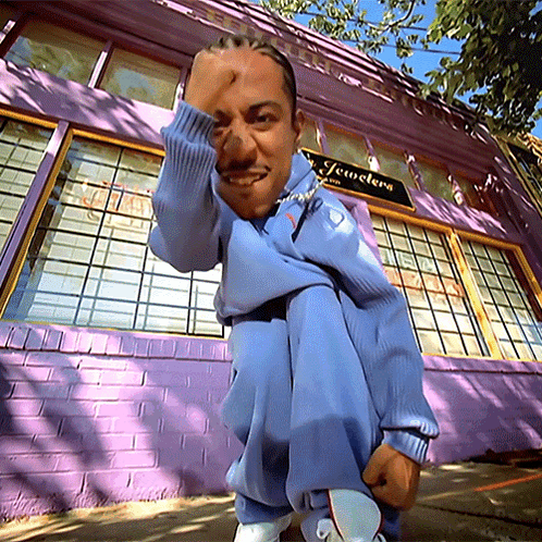 Man Squatting In Front Of Purple Jewelry Building GIF