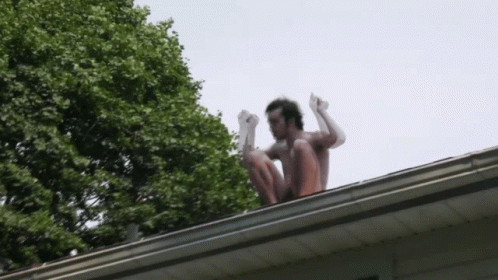 Man Squatting on Roof with Arms Up