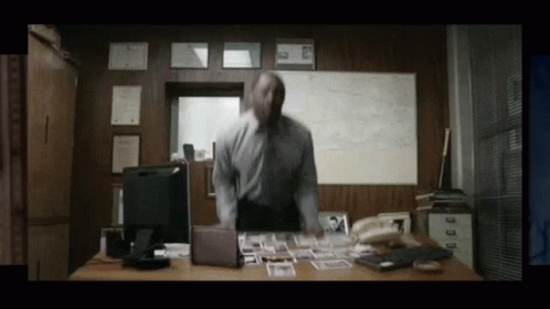Man Standing at Desk with Computer and Phone