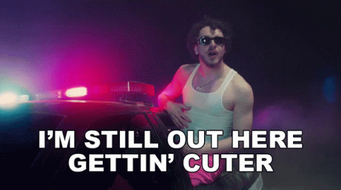 Man Standing by Police Car Saying I'm Still Out Here Gettin' Cuter