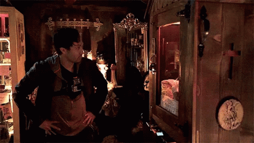 Man Standing In Dark Room Looking At Mirror GIF
