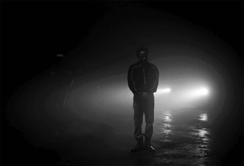 Man Standing in Darkness Behind Car