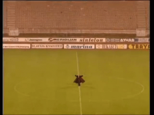 Man Standing in Empty Soccer Stadium with Ads