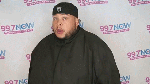 Man Standing in Front of 99.7 Now Wall