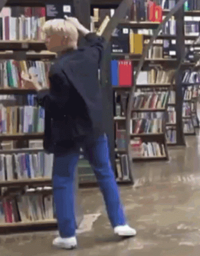 Man Standing in Front of Bookshelf in Bookstore