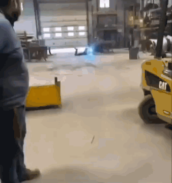Man Standing in Front of Cat Forklift