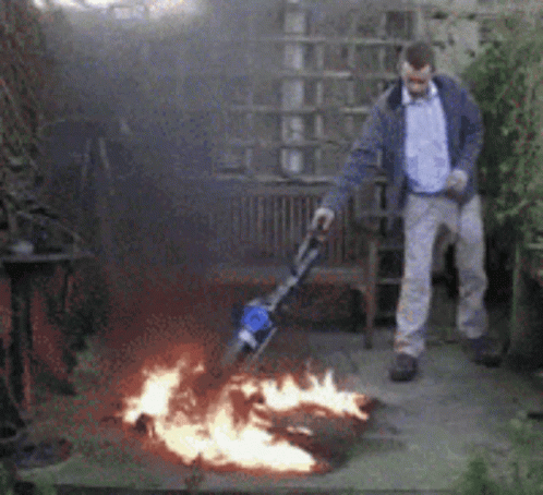 Man Standing in Front of Fire with Vacuum