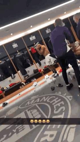 Man Standing in Locker Room With Manchester Logo