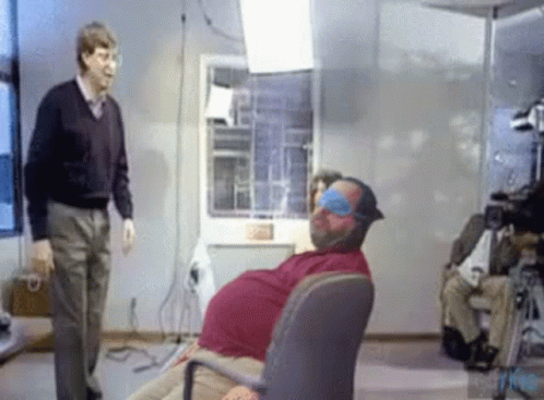 Man Standing Next to Blindfolded Man in Chair