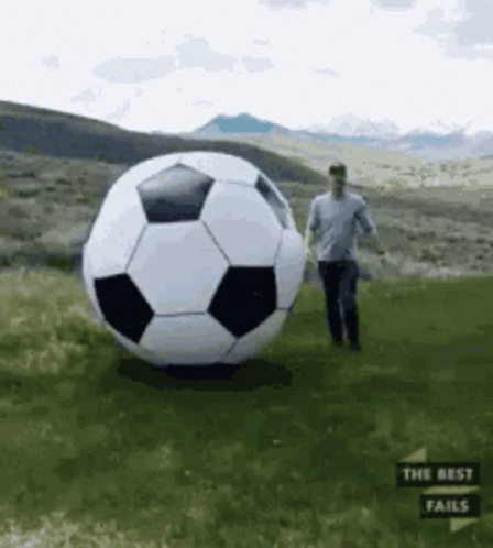 Man Standing Next to Large Soccer Ball