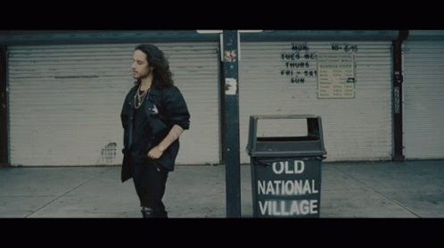 Man Standing Next To Old National Village Garbage Can GIF