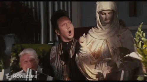Man Standing Next to Veiled Woman Statue