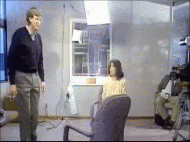 Man Standing Next to Woman in Chair