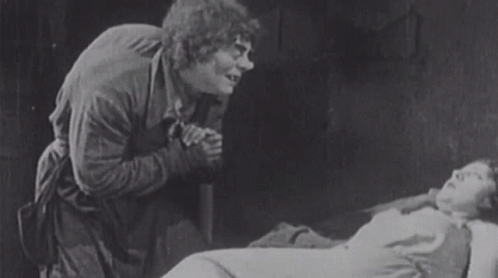 Man Standing Next To Woman Laying In Bed GIF