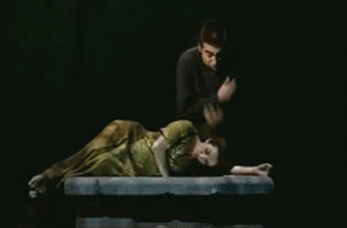 Man Standing Next to Woman Lying