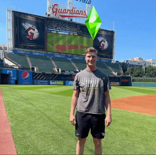 Man Standing on Baseball Field in Front of Guardians Sign