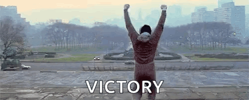 Man Standing on Ledge with Victory