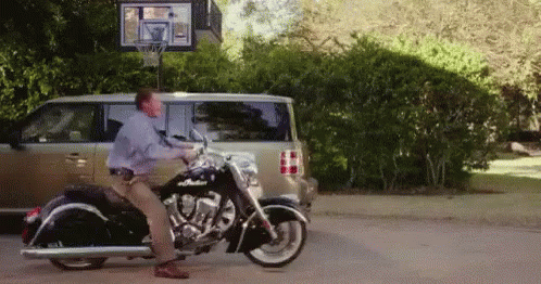 Man Standing on Motorcycle in Front of Van