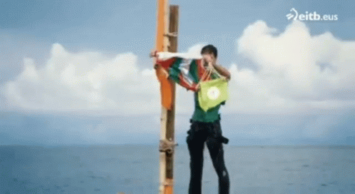 Man Standing on Pole in Ocean eitb.eus
