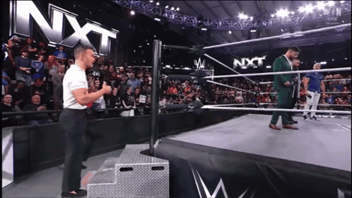 Man Standing On Stage In Front Of NXT Sign GIF