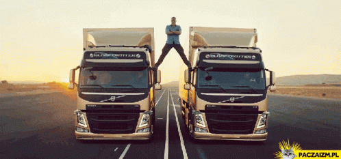 Man Stands on Top of Two Volvo Trucks