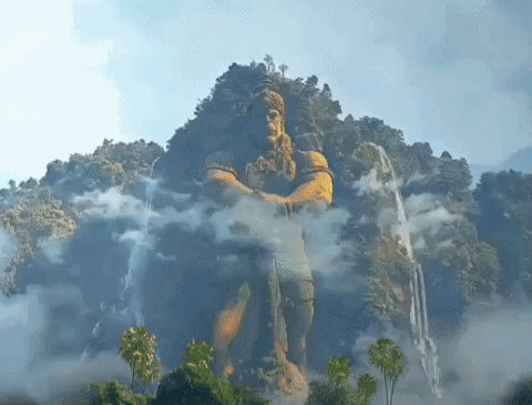 Man Statue on Mountain with Trees and Clouds