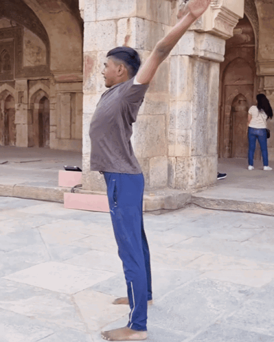 Man Stretching Arms in Front of Stone Building