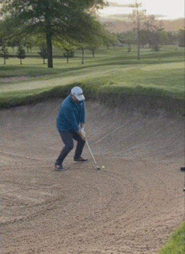 Man Swinging Golf Club at Ball in Bunker