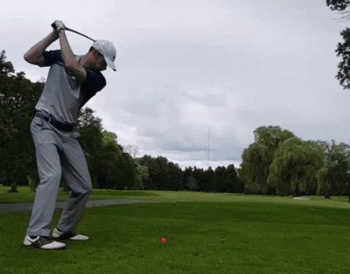 Man Swinging Golf Club at Red Ball