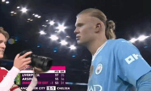 Man Taking Photo of Soccer Player in Blue Shirt