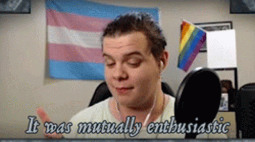 Man Talking Into Microphone With Rainbow And Transgender Flags GIF